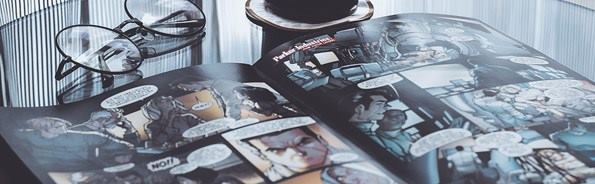 Comic abierto en mesa, lentes y café